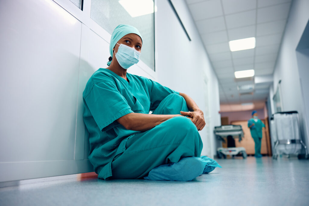Tired female surgeon siting on floor in hospital hallway